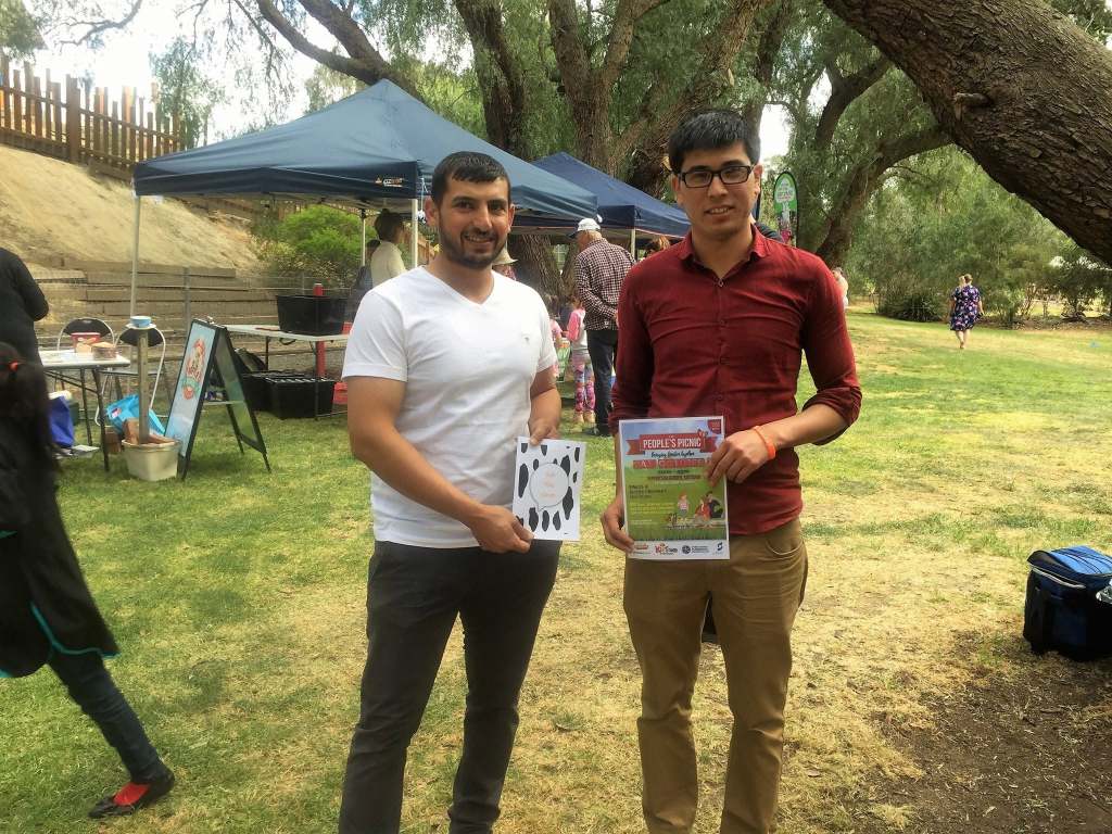 Hussam Saraf and another participant holding books at an outdoor community event.
