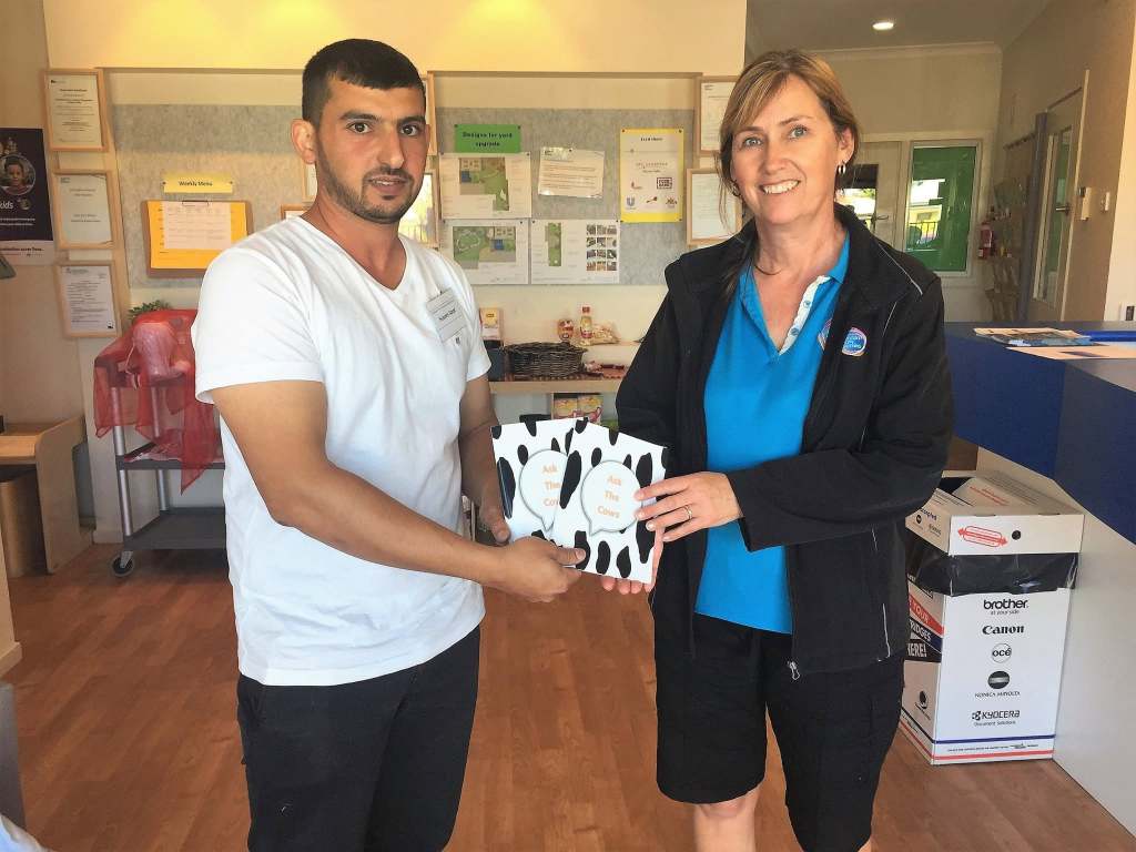 Hussam Saraf presenting Ask the Cows to a staff member at a local reception desk.