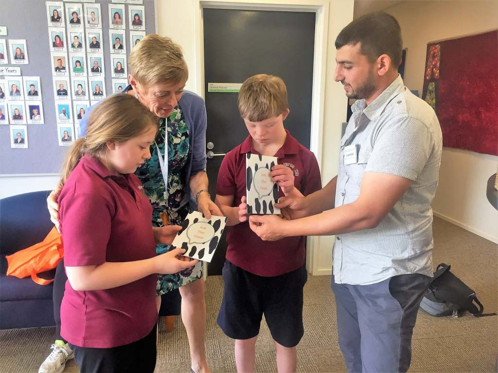 Hussam Saraf and a staff member exploring Ask the Cows with two students.