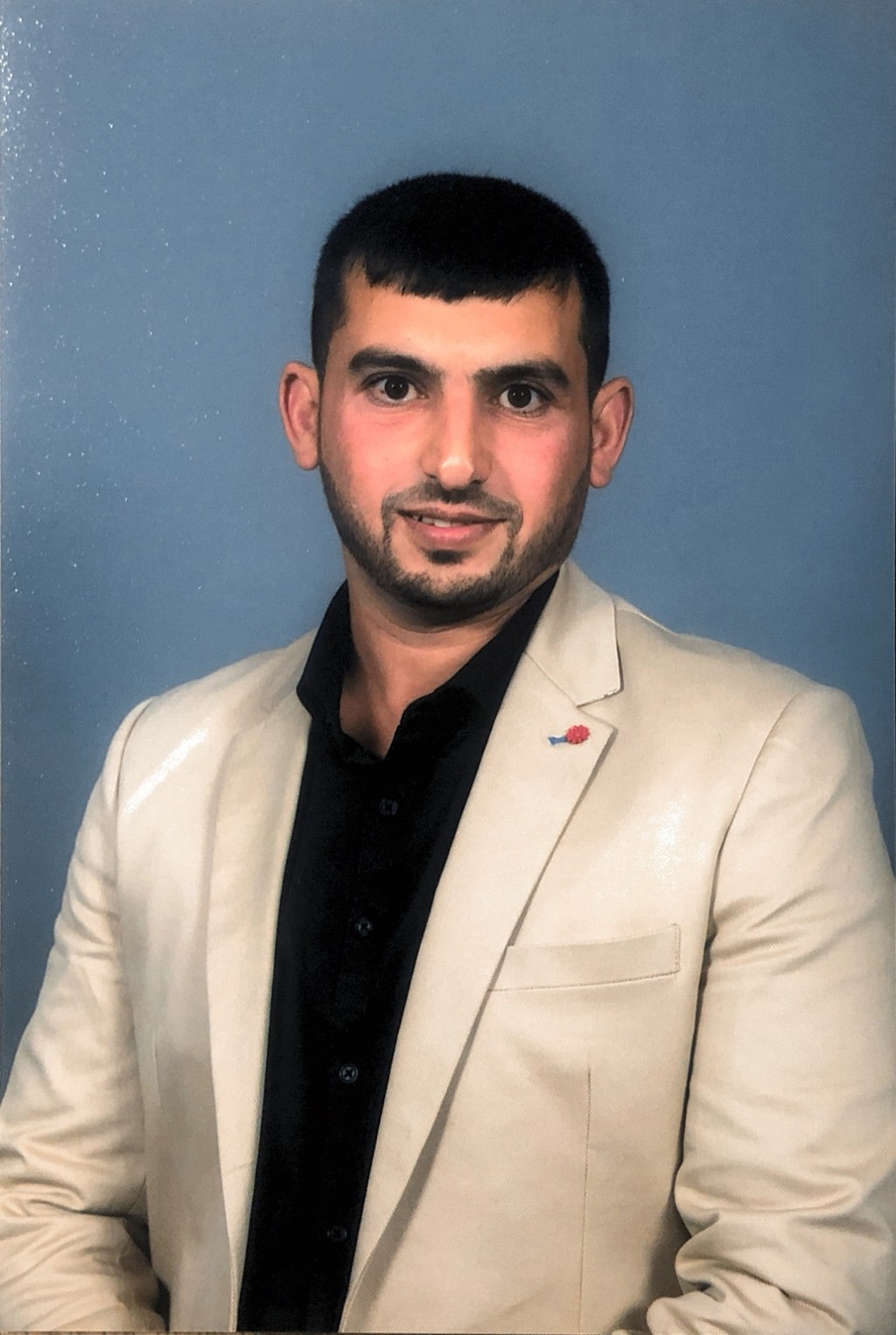 A seated portrait of Hussam Saraf in a light-coloured jacket on graduation day in 2017.