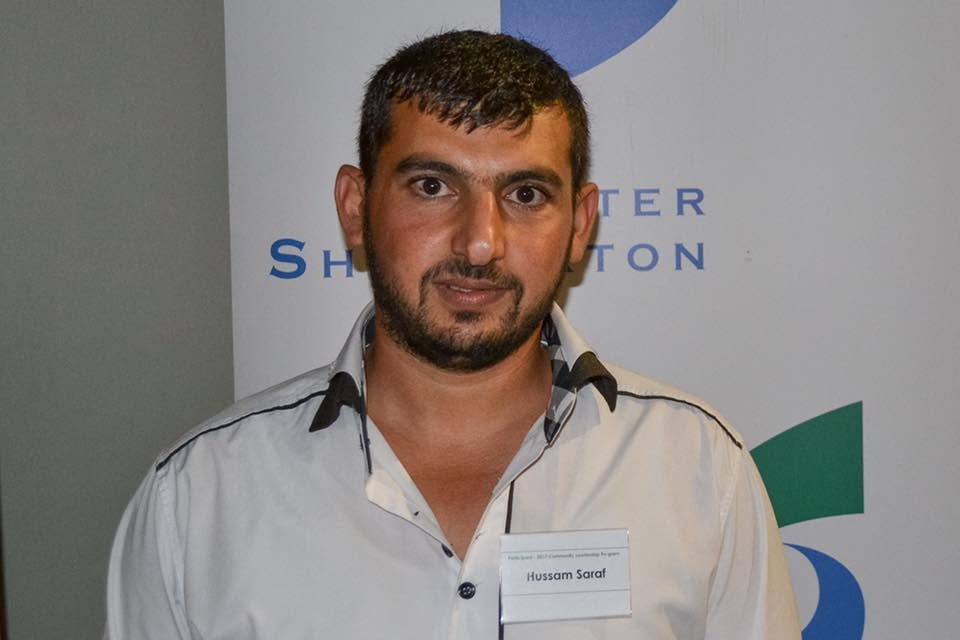Hussam Saraf wearing his Community Leadership Program name badge in front of a Greater Shepparton banner.