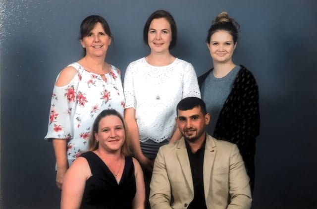Hussam Saraf seated with four fellow attendees in a portrait from the 2017 program graduation.