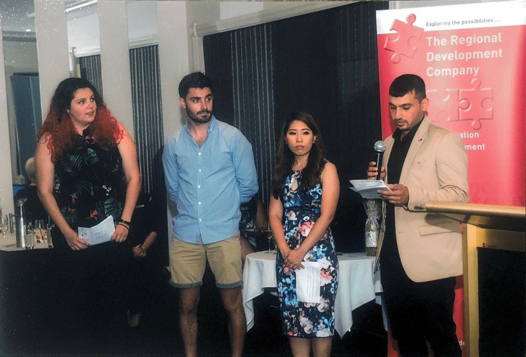 Hussam Saraf speaking from his notes alongside three fellow participants at the 2017 graduation.