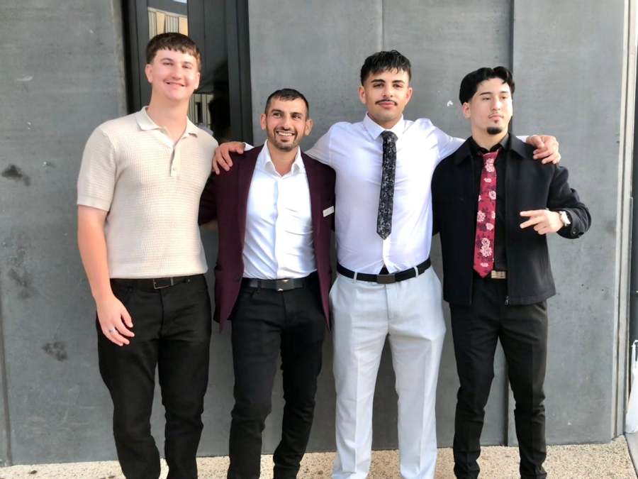 Four people in formal clothing posing beside a grey campus wall. GSSC Class of 2025.