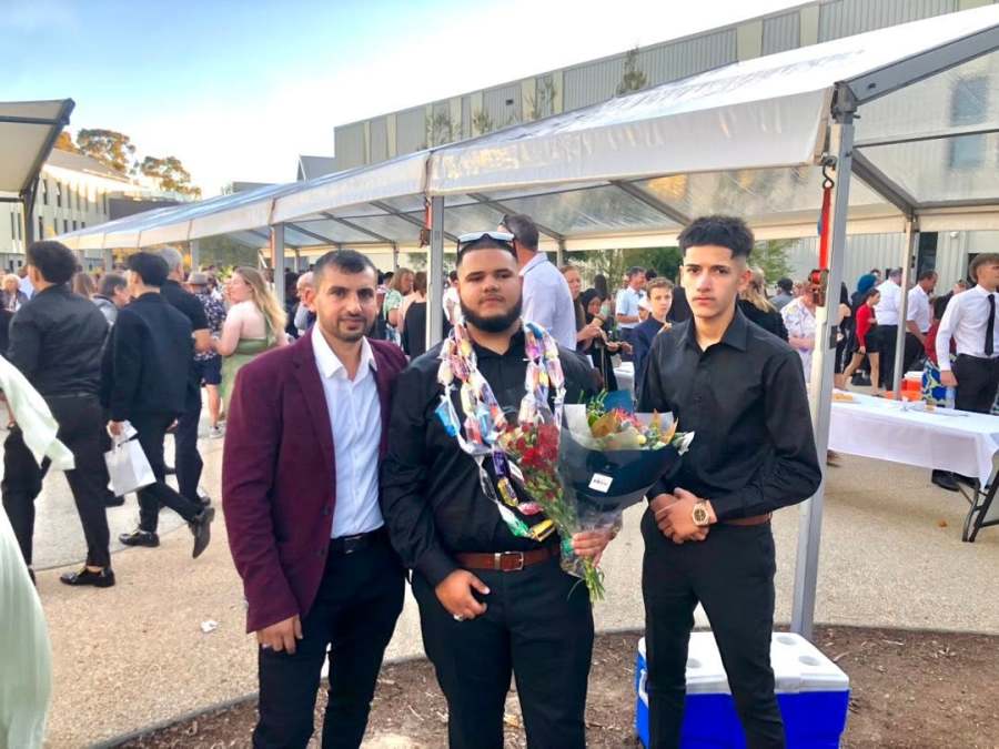 A wider view of three people with flowers among the graduation gathering. GSSC Class of 2025.
