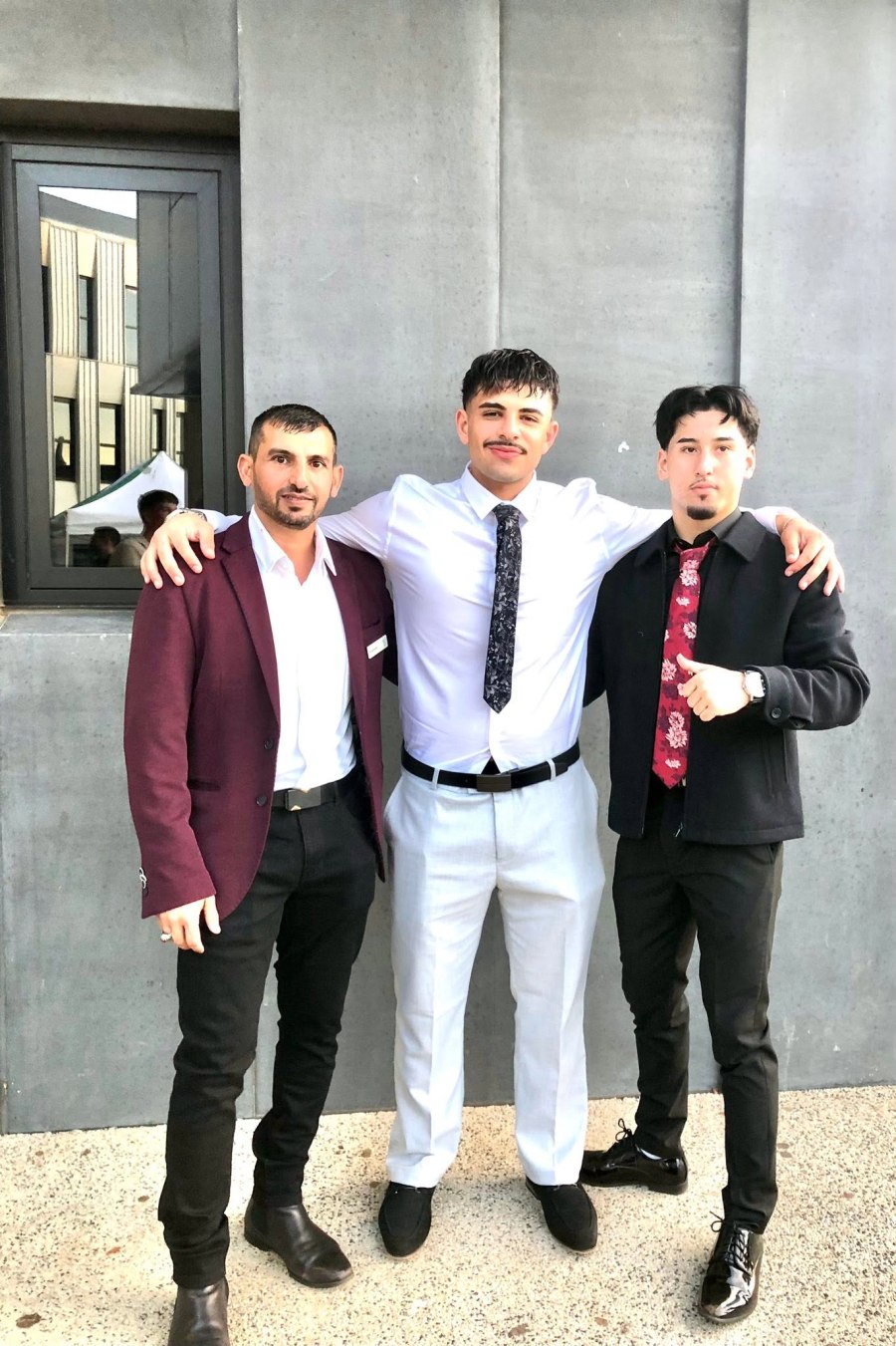 A full-length portrait of three people in formal clothing beside a grey wall. GSSC Class of 2025.