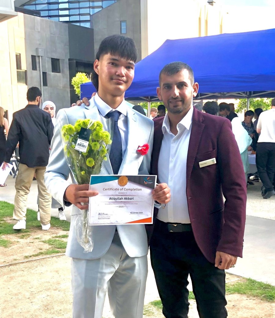 A graduate holding flowers and a certificate beside a staff member. GSSC Class of 2025.