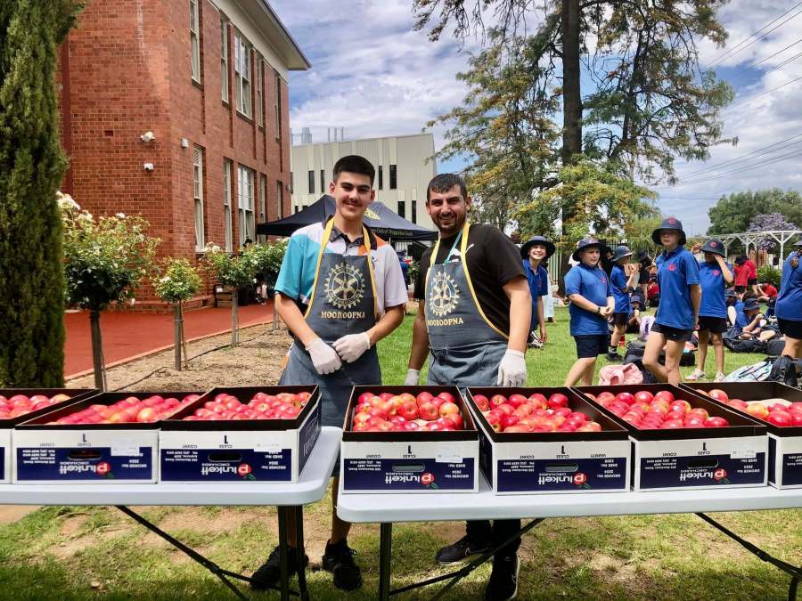 Student and adult volunteers in Rotary Mooroopna aprons beside the food tables.
