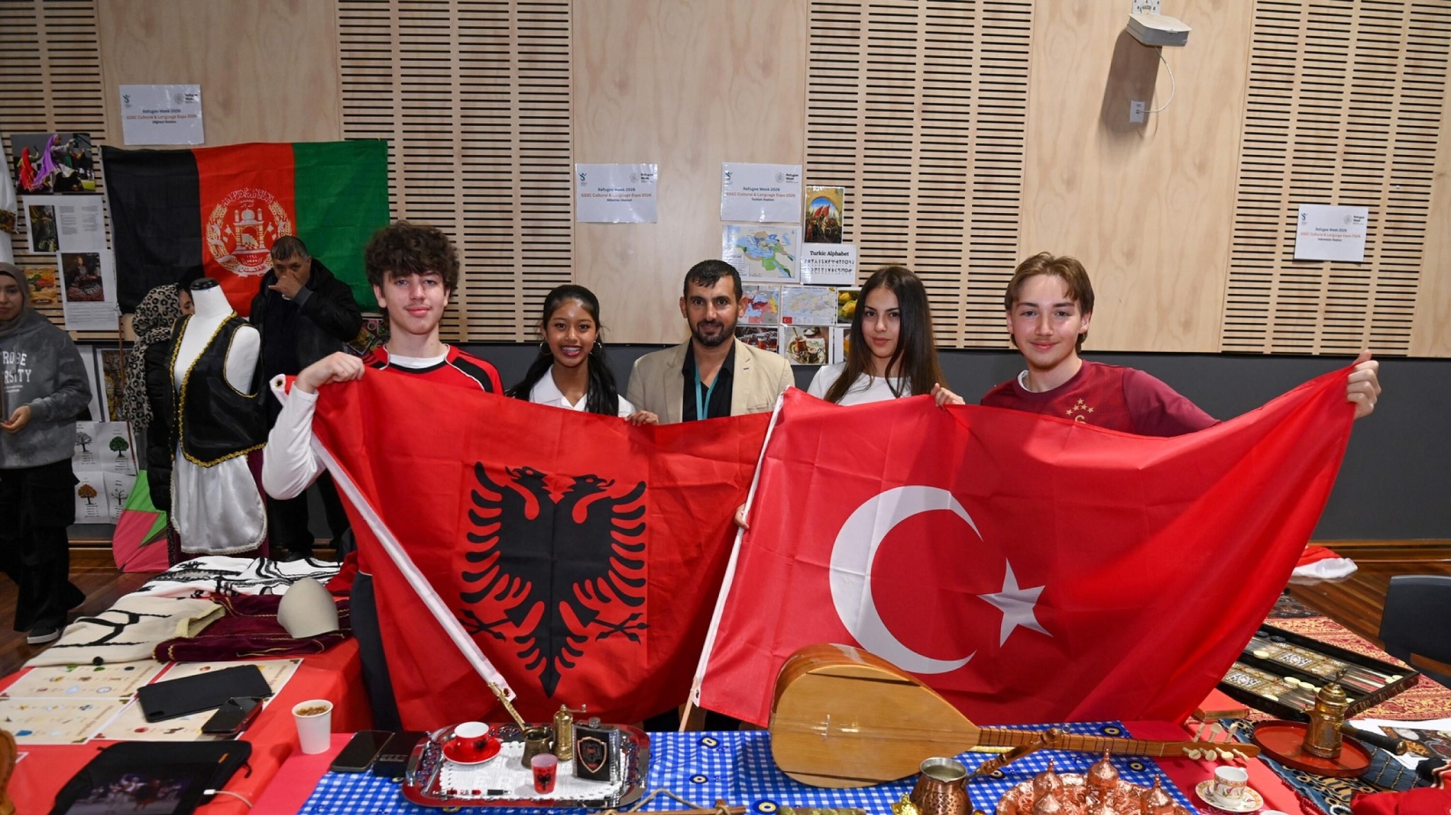 Hussam Saraf with students at GSSC’s Cultural and Language Expo, holding Albanian and Turkish flags.