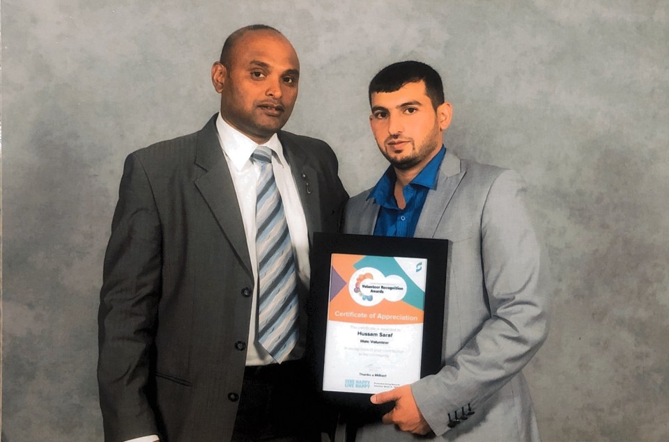 Hussam Saraf with another attendee, holding his 2017 Male Volunteer Certificate of Appreciation.