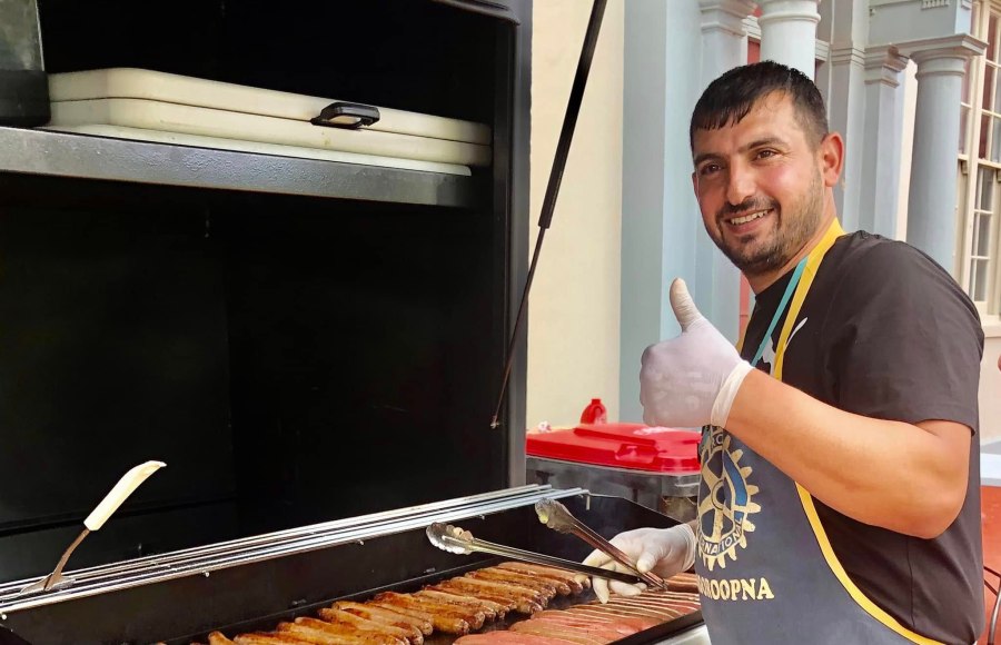 Volunteer wearing a Rotary Mooroopna apron and preparing sausages at the GSSC Year 5 Aspirations Day barbecue.
