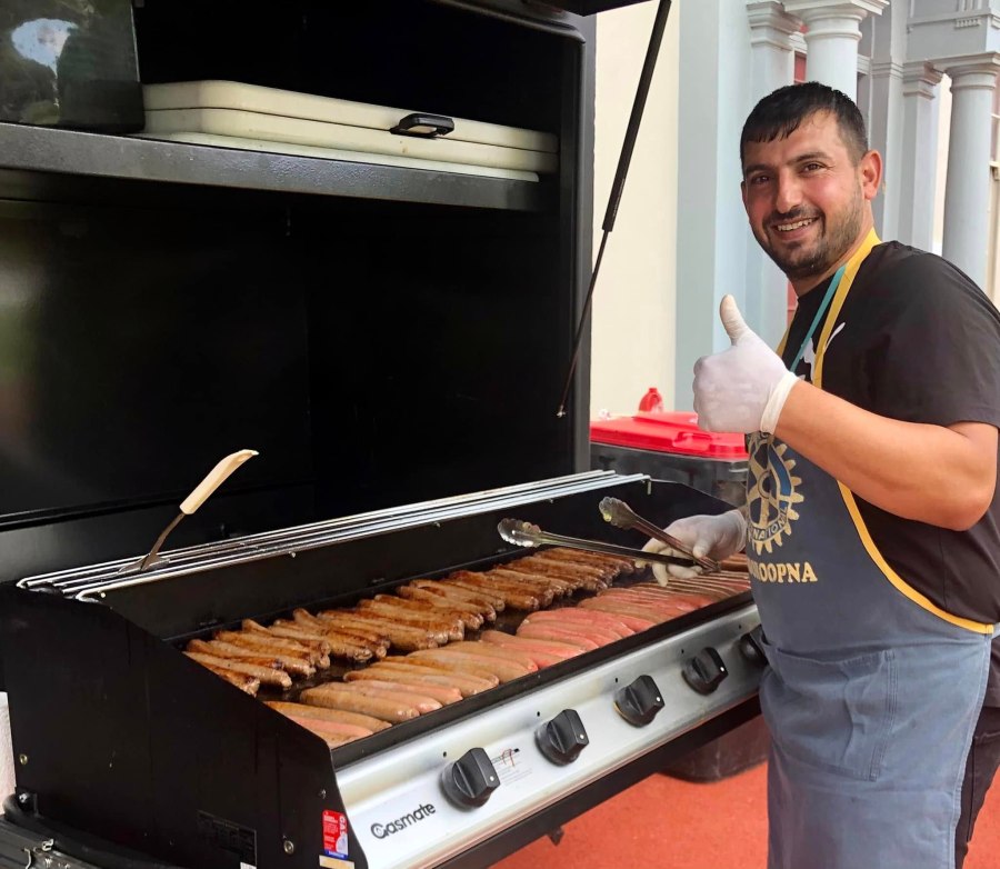 Volunteer in a Rotary Mooroopna apron beside the barbecue at GSSC Year 5 Aspirations Day.