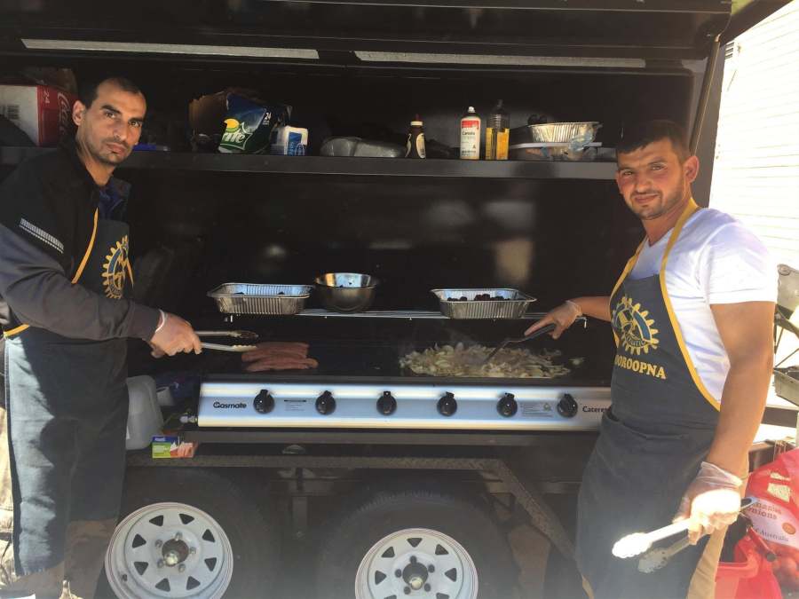 Two volunteers cooking sausages and onions at the Rotary barbecue.