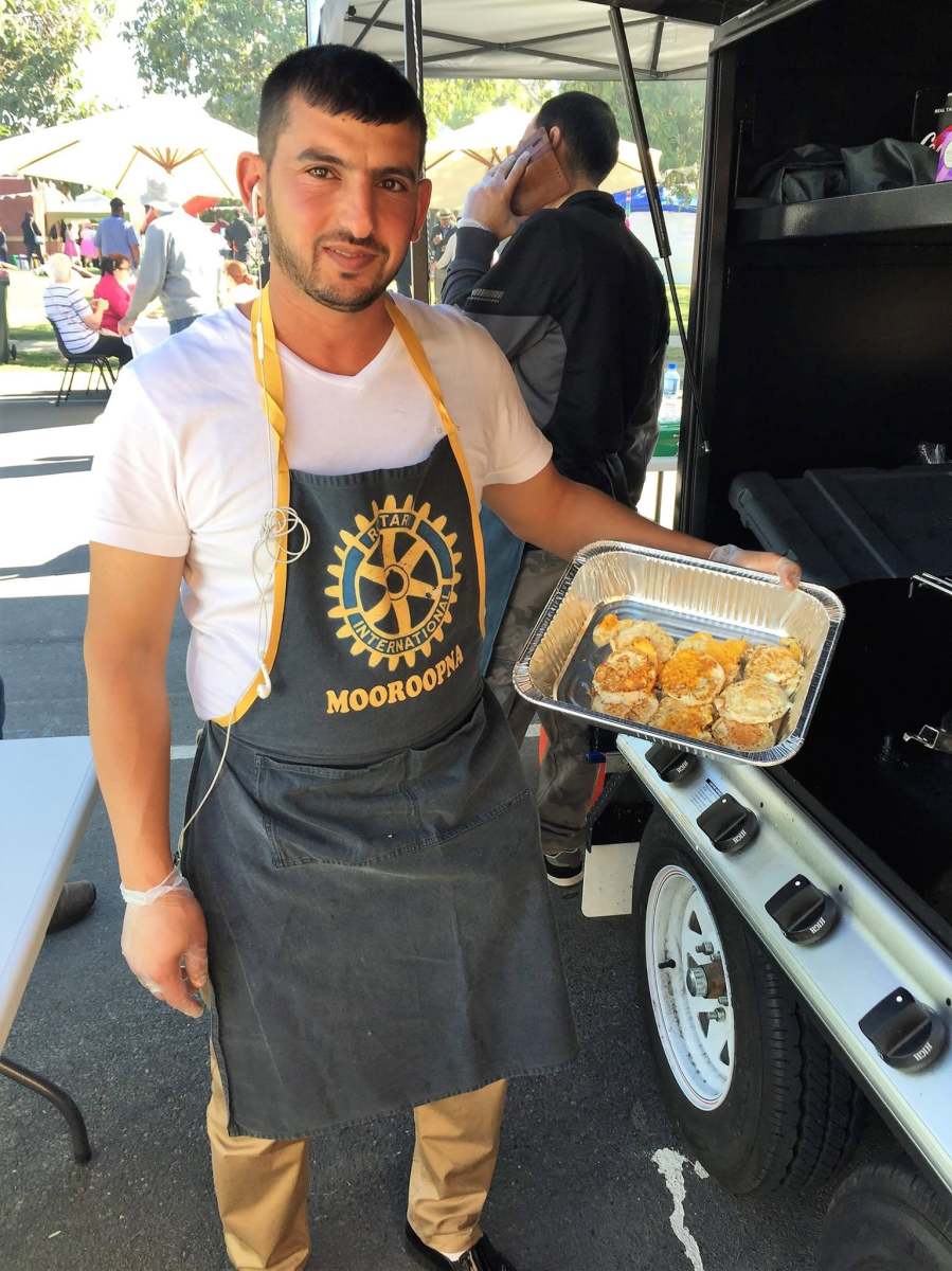 A volunteer in a Rotary Mooroopna apron holding a tray of cooked eggs.