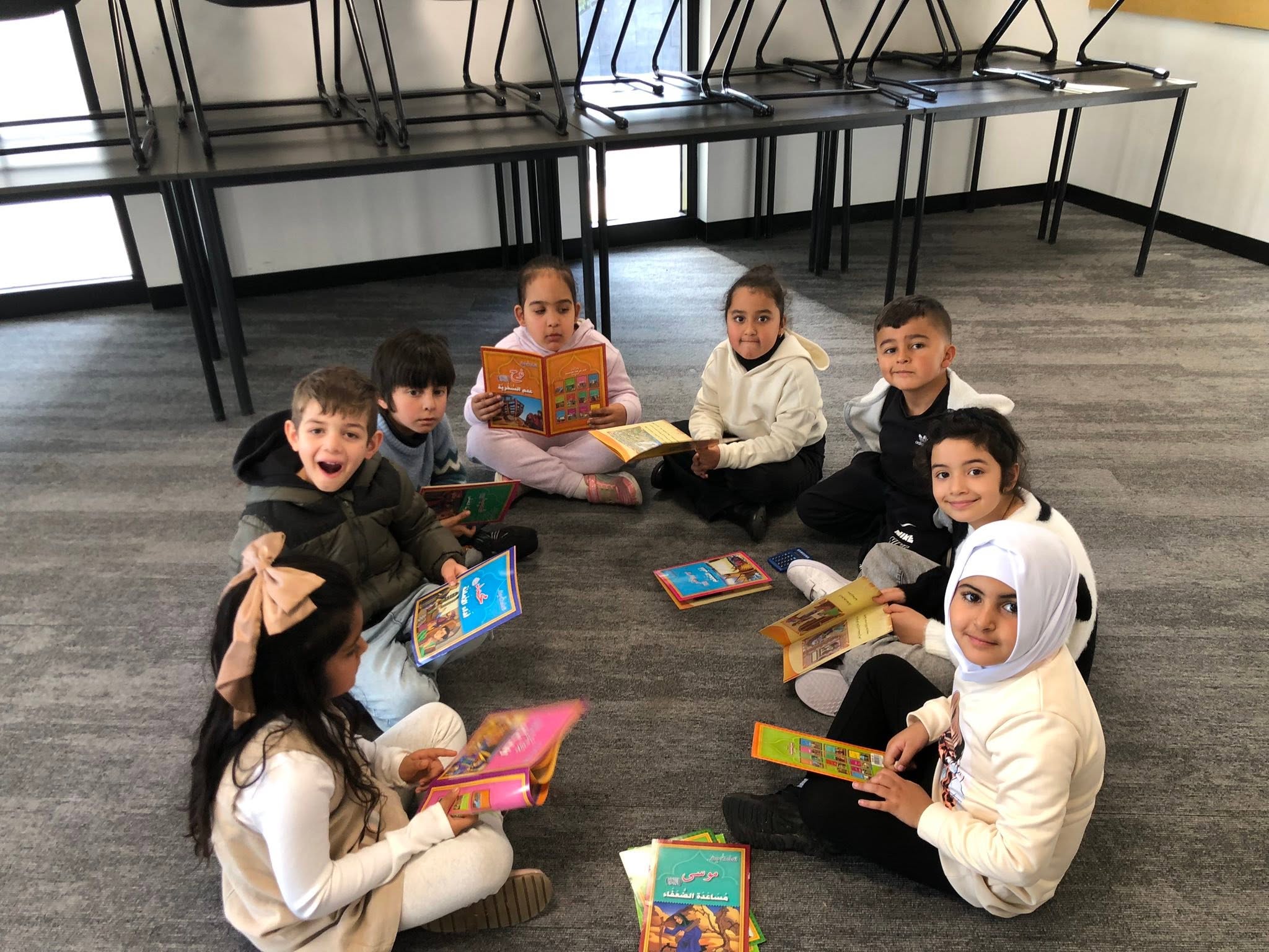Children sitting together with books in a classroom reading circle.