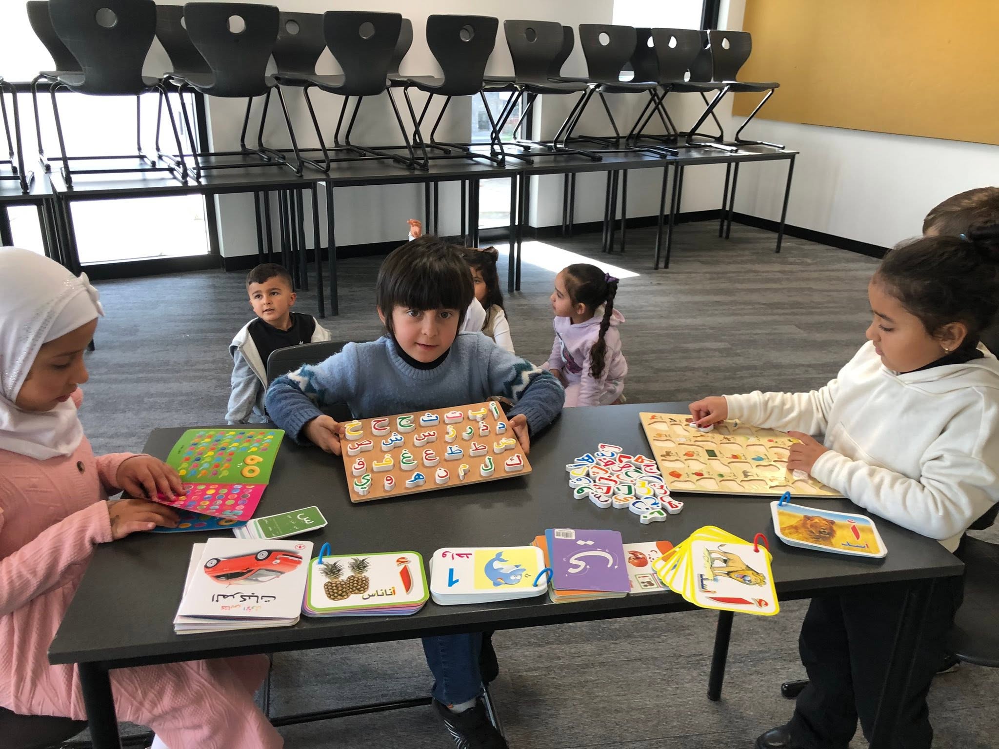 Young learners using books and puzzles together at a classroom table.