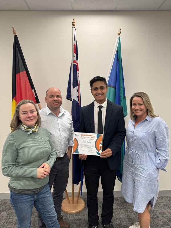 Safa Zahir holding his Brian Birrell Advocacy Award, with Sam Birrell and members of the Birrell family.