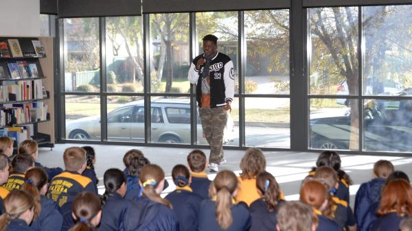 Students seated in Tatura Library watching a singer perform during the GSSC Refugee Week event.