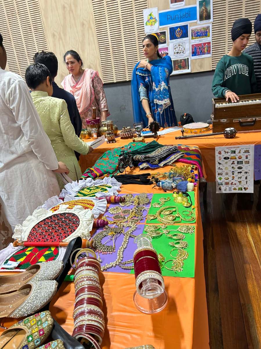 Expo participants beside a display of colourful textiles and cultural objects.