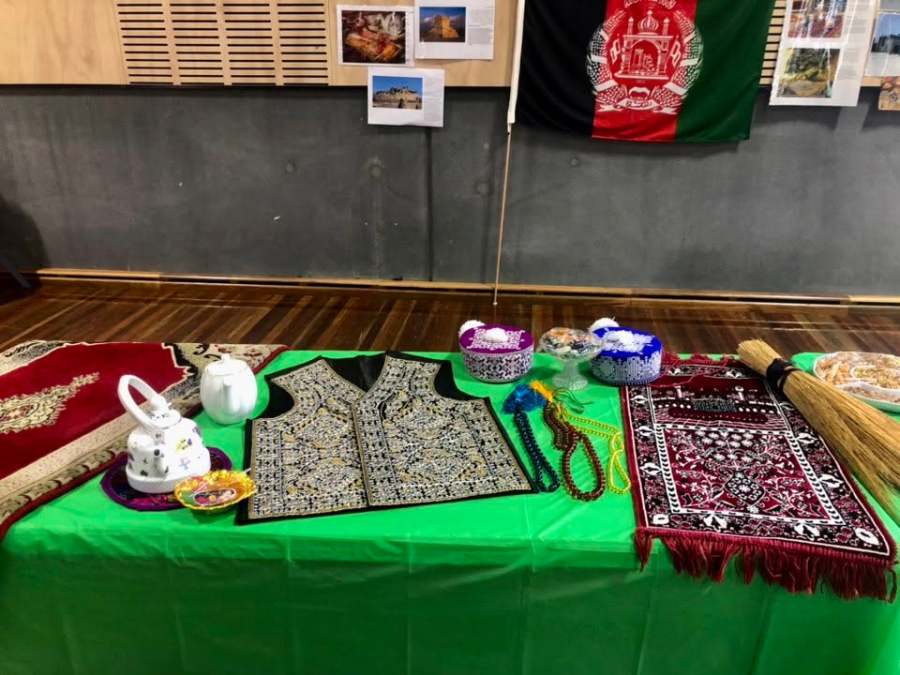 A table with cultural textiles, teapots and other objects beneath display posters.