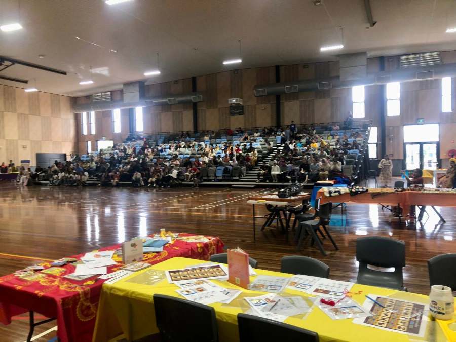 Language station tables in the foreground and the seated audience beyond.